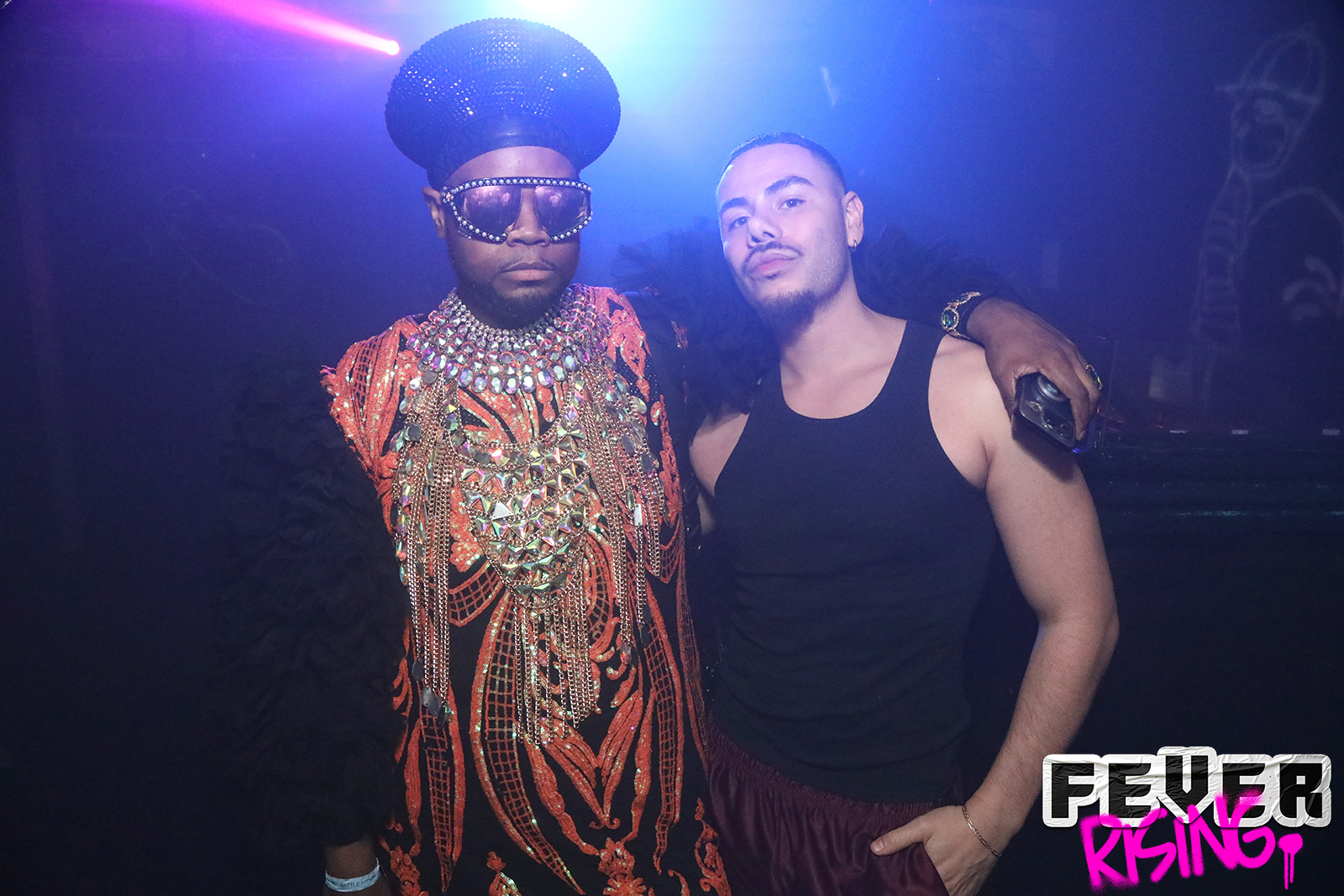 Guest in a crystal-covered headpiece and cape posing with a friend
