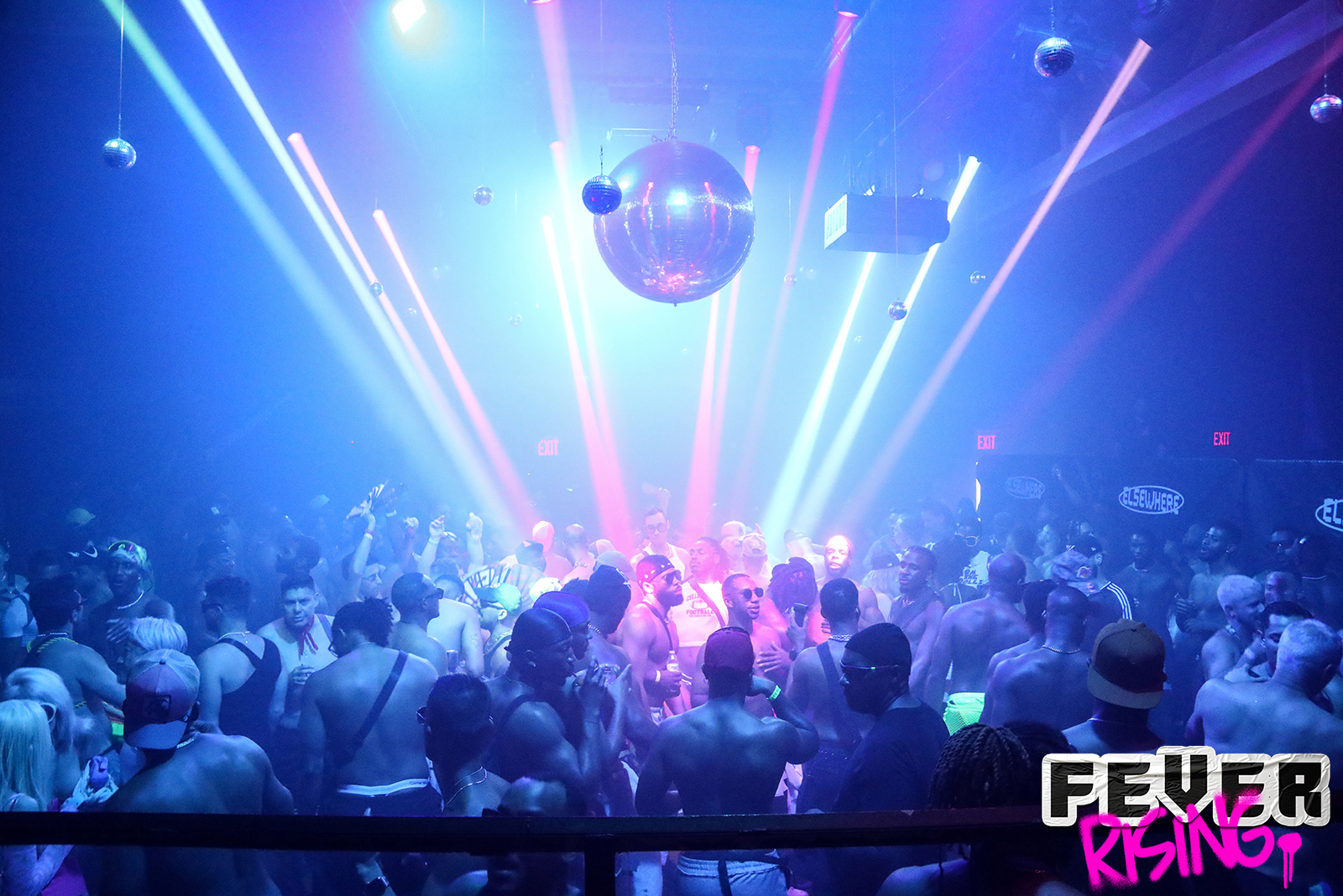Packed dance floor under laser beams and a giant disco ball